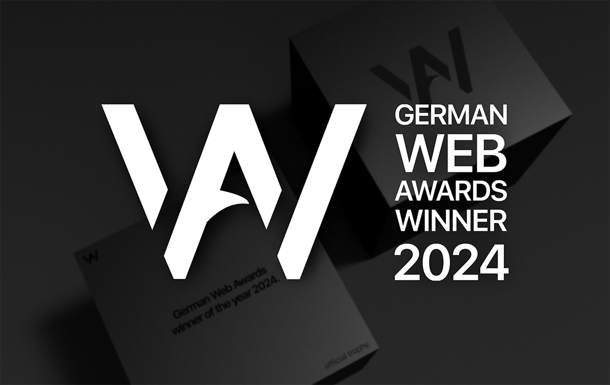 Logo und Schrift German Web Award Winner 2024. Im Hintergrund ist verschwommen die schwarze Trophäe in Würfelform zu sehen.